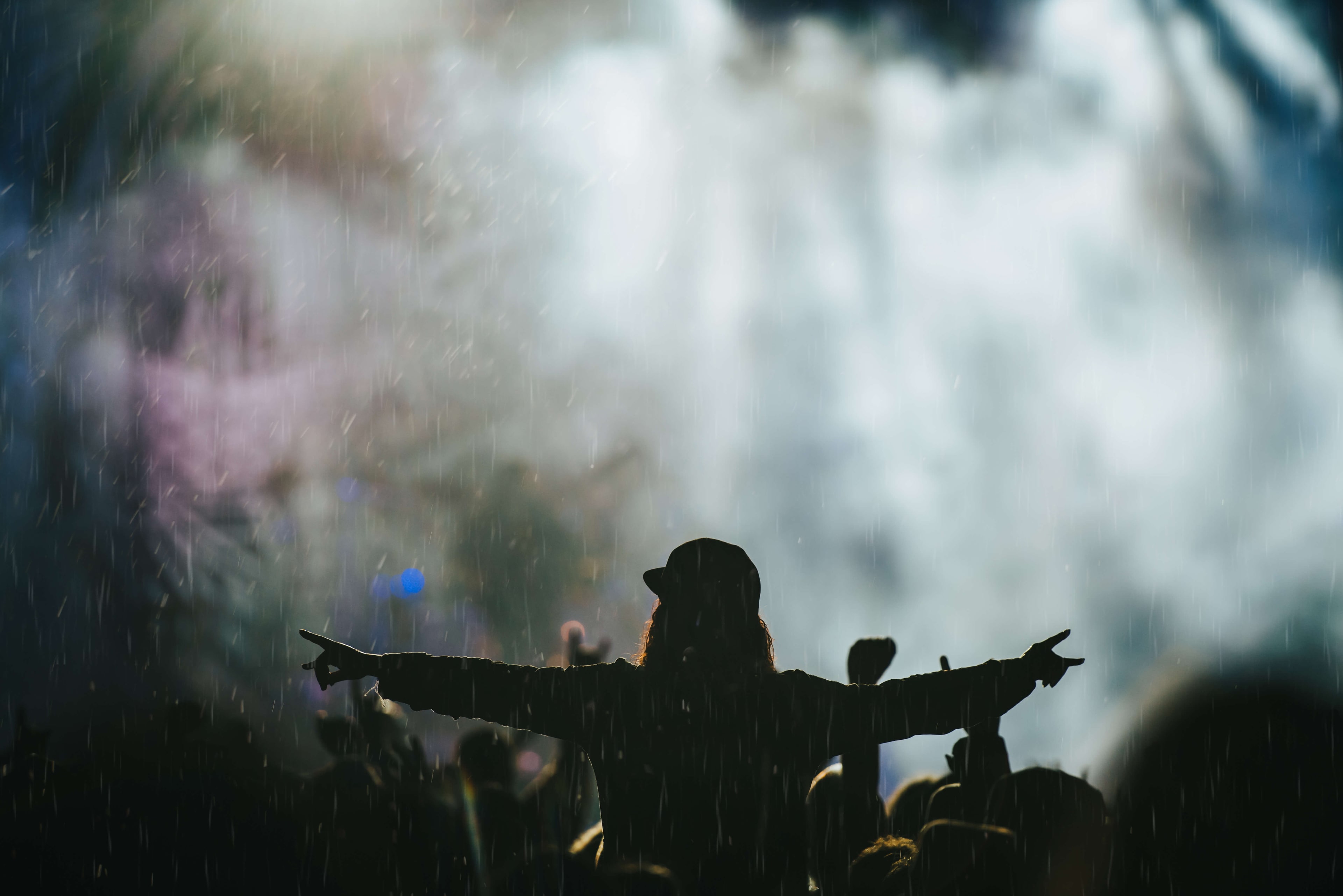 Performer facing a concert crowd beneath stage lights